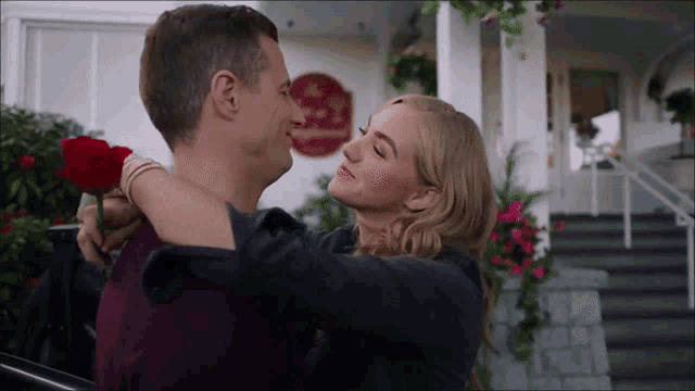 a man and a woman are kissing in front of a hotel