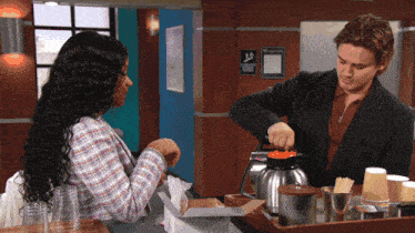 a man pours coffee into a coffee pot while a woman watches