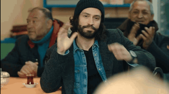 a man with a beard wearing a hat and a denim jacket