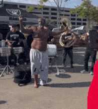 a shirtless man stands in front of a band wearing raiders jerseys