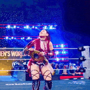 a woman is standing in a wrestling ring holding a belt .
