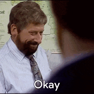 a man with a beard is smiling and talking to another man while wearing a shirt and tie .