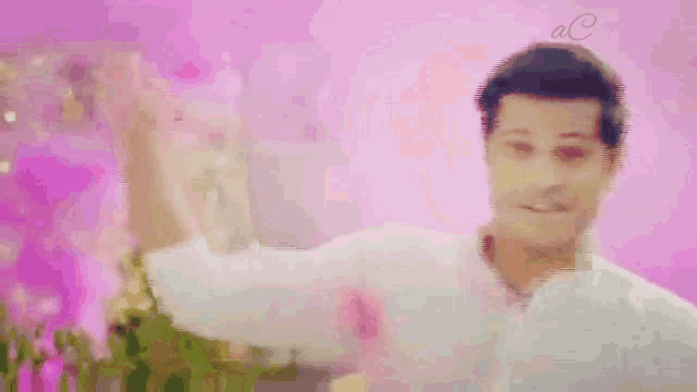 a man in a white shirt is standing in front of a pink background with the letters ac on it