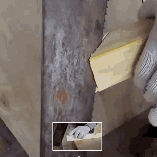 a person is cutting a piece of wood with a saw and the time is 3:25
