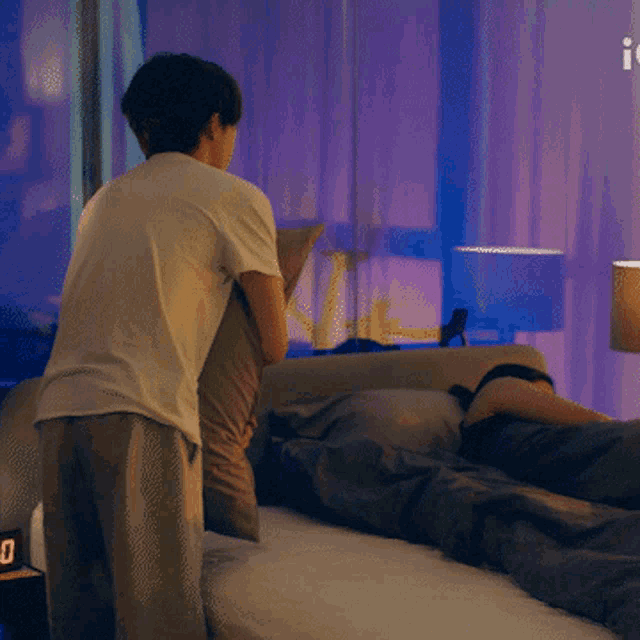 a man laying on a bed next to a clock that reads 50