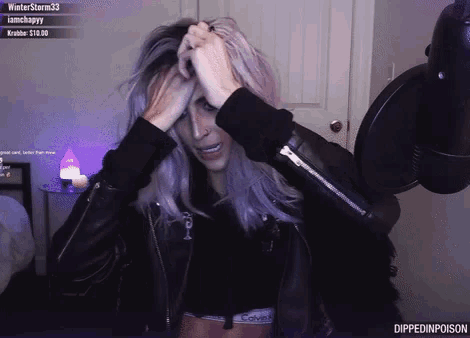 a woman wearing a black jacket and a calvin klein top holds her head