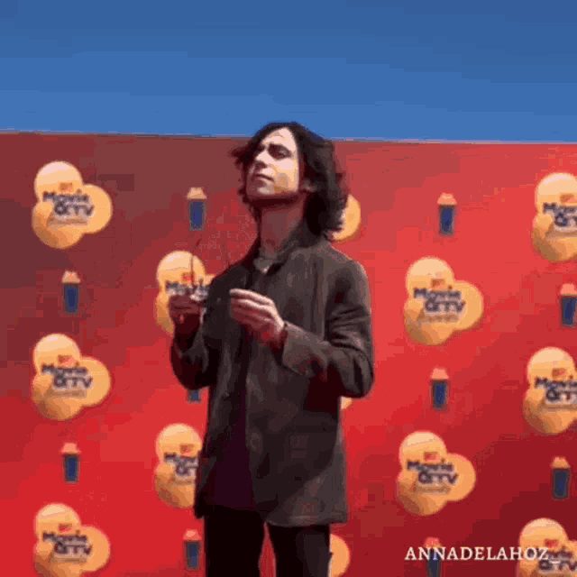 a man stands in front of a red wall that says mtv movie & tv