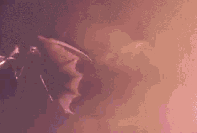 a bat is flying through the air in a dark room with smoke coming out of its mouth .