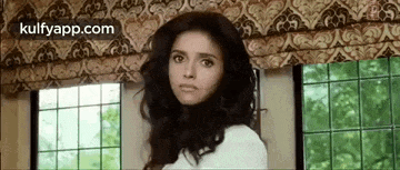 a woman is standing in front of a window in a room and looking at the camera .