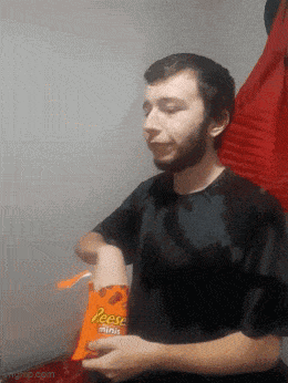 a man in a black shirt holds a bag of reese 's minis