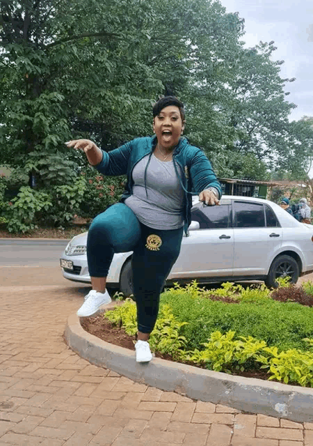 a woman is standing on one leg in front of a car