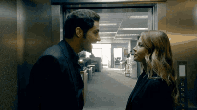 a man and a woman are looking into each other 's eyes in an elevator