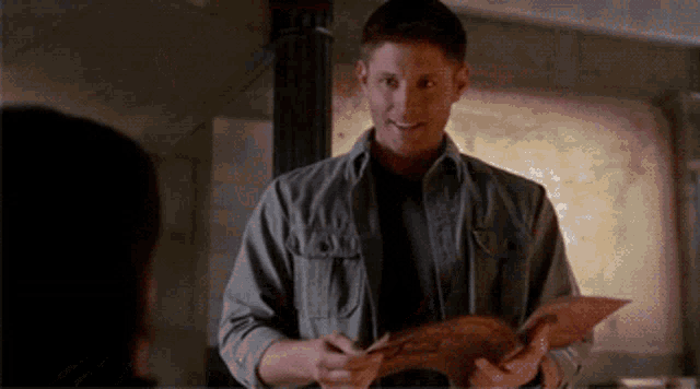 a man in a grey shirt is holding a book