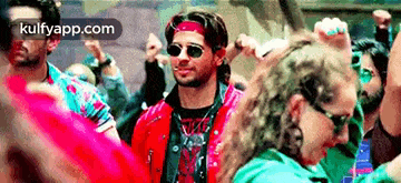 a man wearing sunglasses and a bandana is dancing in a crowd of people .