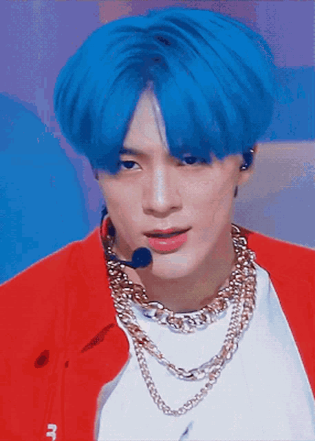 a man with blue hair is wearing a red jacket