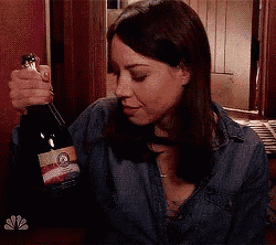 a woman is holding a bottle of wine with a label that says ' nbc ' on it