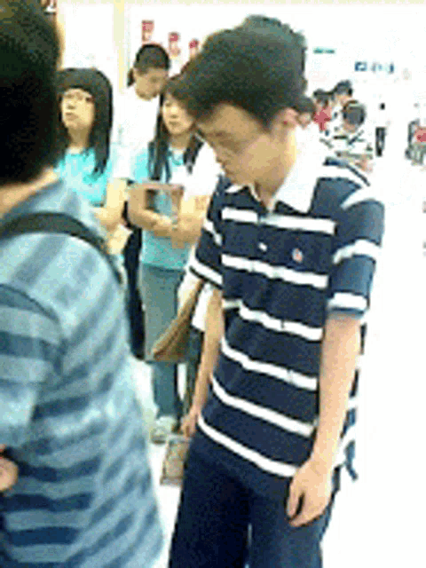 a man in a blue and white striped shirt stands in front of a crowd of people