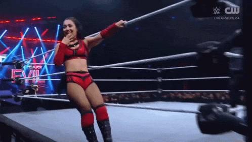 a woman in a wrestling ring with a cw logo on the bottom