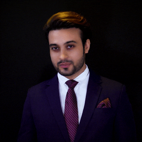 a man in a purple suit and tie is giving the ok sign