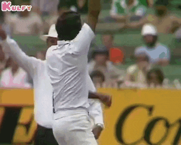 a man in a white shirt is throwing a ball in the air while a referee watches .