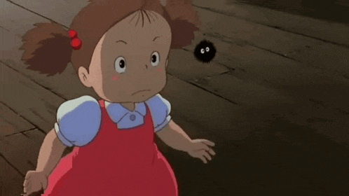 a little girl in a red dress is sitting next to a black object with the letters co on it .