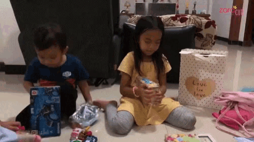 a boy and a girl sit on the floor with a bag that says love for love