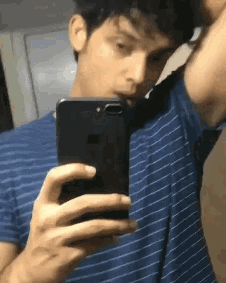 a man is taking a selfie with his phone in front of a mirror .