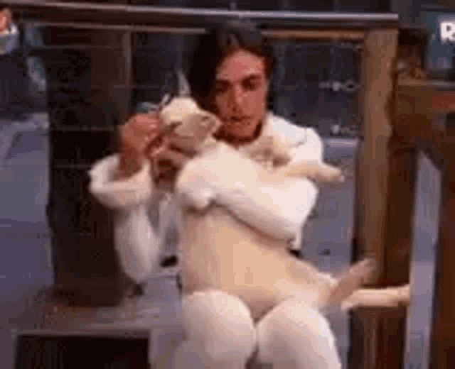 a man in a white suit is holding a stuffed animal .