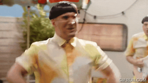 a man in a yellow shirt is dancing in front of a trailer and a sign that says gifrun.com