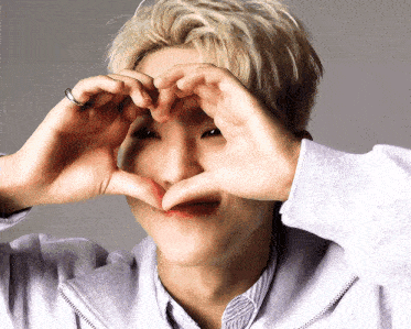 a man making a heart with his hands in front of his face