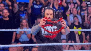 a man in a wrestling ring is holding a red rope in his mouth .