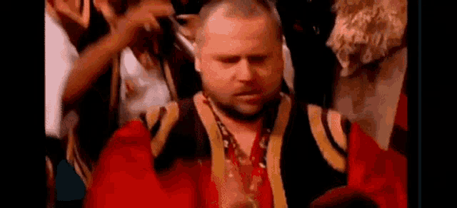a man in a red and gold costume is standing in a crowd .