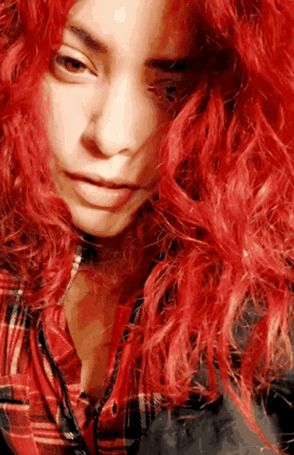 a woman with red hair is wearing a plaid shirt and headphones