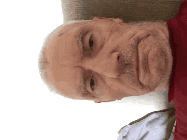 a man with a beard and a red shirt looks down at the camera