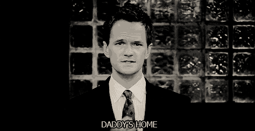 a man in a suit and tie says " daddy 's home " in a black and white photo