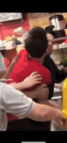 a group of people are hugging each other in a kitchen .