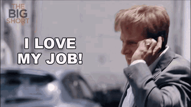 a man in a suit talking on a cell phone with the words i love my job above him