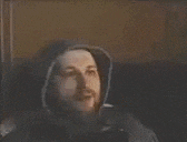 a man in a hooded jacket is giving a thumbs up sign .