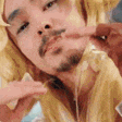 a man with a beard is eating french fries while wearing a wig .