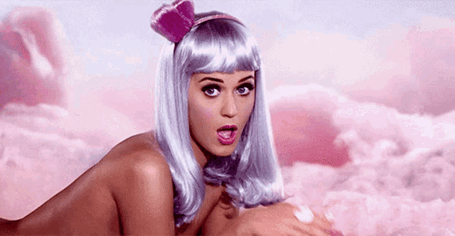 a naked woman wearing a purple wig and a pink headband is laying on a bed of pink clouds .