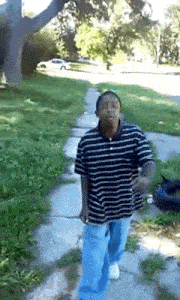 a man walking down a sidewalk wearing a striped shirt