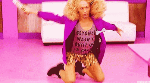 a woman in a purple jacket and leopard print shorts is kneeling on the floor holding a broom .