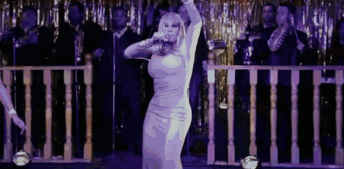 a woman in a white dress is dancing on a stage in front of a crowd .