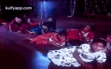 a group of people are laying on their stomachs on the floor in a dark room .