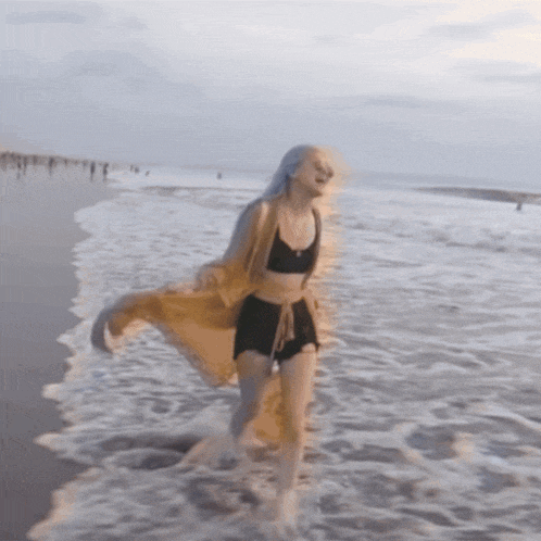 a woman in a bikini and shorts is running in the water