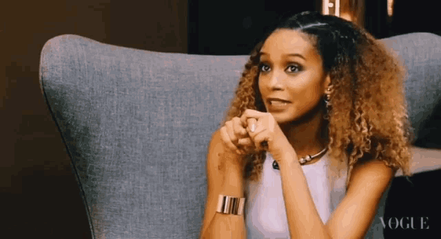 a woman with curly hair sits in a chair with the word vogue on the bottom