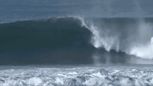a large wave is breaking in the ocean on a sunny day