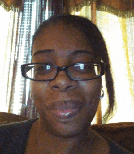 a woman wearing glasses and earrings is smiling for the camera
