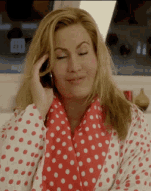 a woman wearing a red and white polka dot robe is talking on a cell phone .