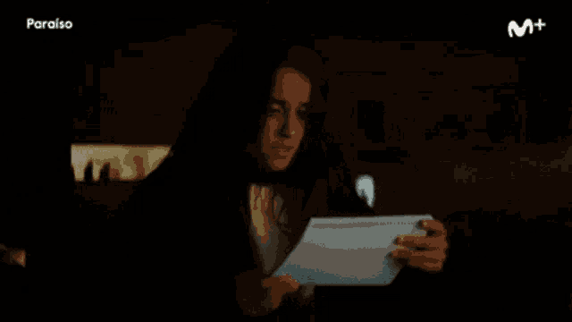 a woman is holding a piece of paper and says mierda .